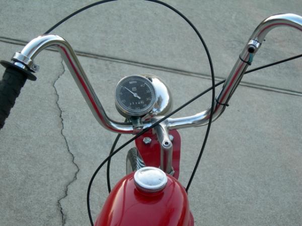 This shows the Wald handlebars, the gooseneck alteration that allows the springer front end to work, and the Stewart Warner speedo. Note the funky hor